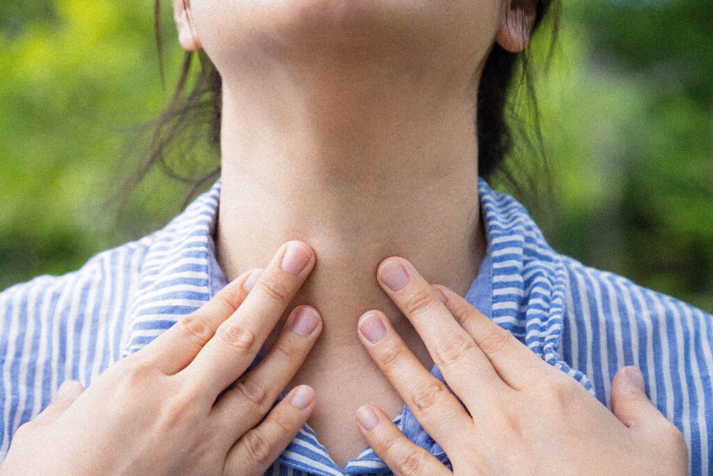 Femme touchant une glande thyroïde dans son cou