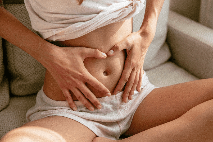 Woman at an early stage of pregnancy creating a heart shape with her hands on her stomach