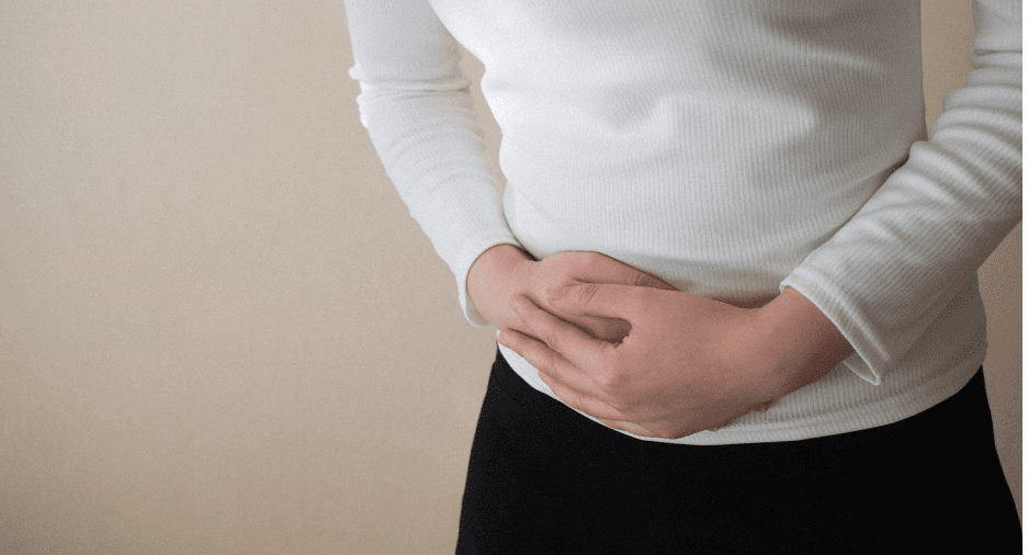 Young woman suffering from stomach pain due to ovarian cancer, on gray background