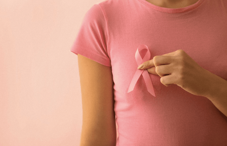 Woman with pink ribbon on pink background for breast cancer awareness month