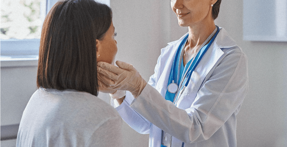 Female doctor performing a thyroid check on a female patient.